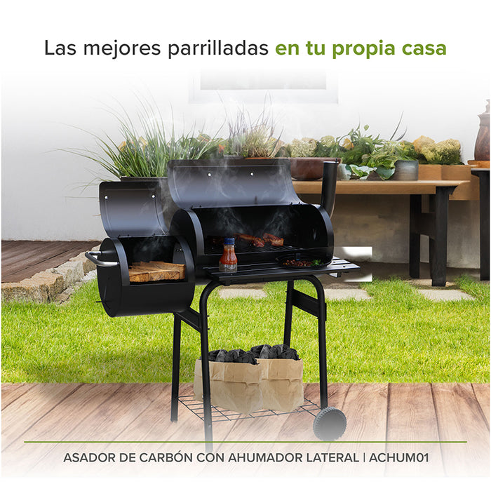 Asador y ahumador con carnes en las parrillas colocado en un jardín exterior.