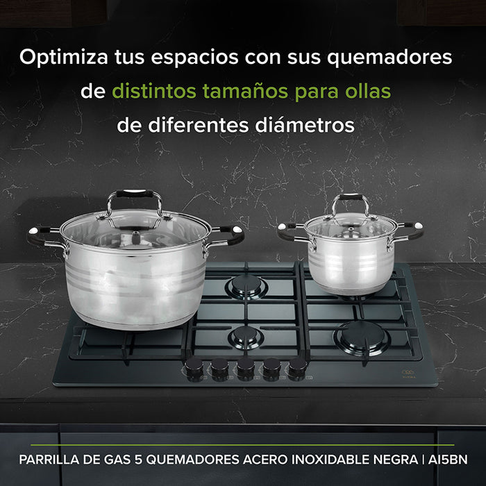 Estufa de acero inoxidable empotrada en mueble de cocina con unas ollas encima.