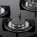 Detalle de quemadores y soportes circulares de hierro fundido sobre superficie de vidrio templado negro.